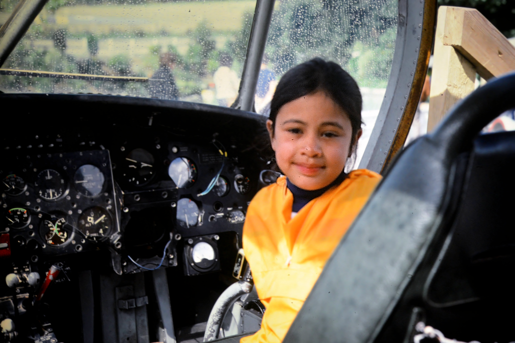 A picture of Georgina as a young child sitting in a cockpit.